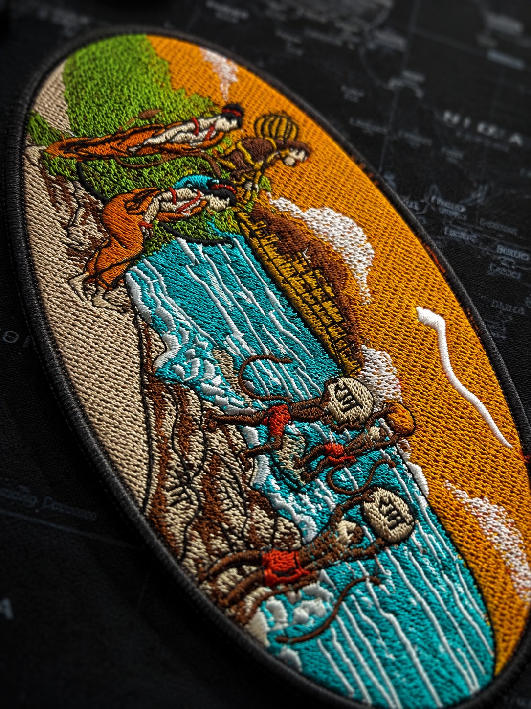 Macro of the Ram Setu embroidery showing satin stitches in turquoise and saffron